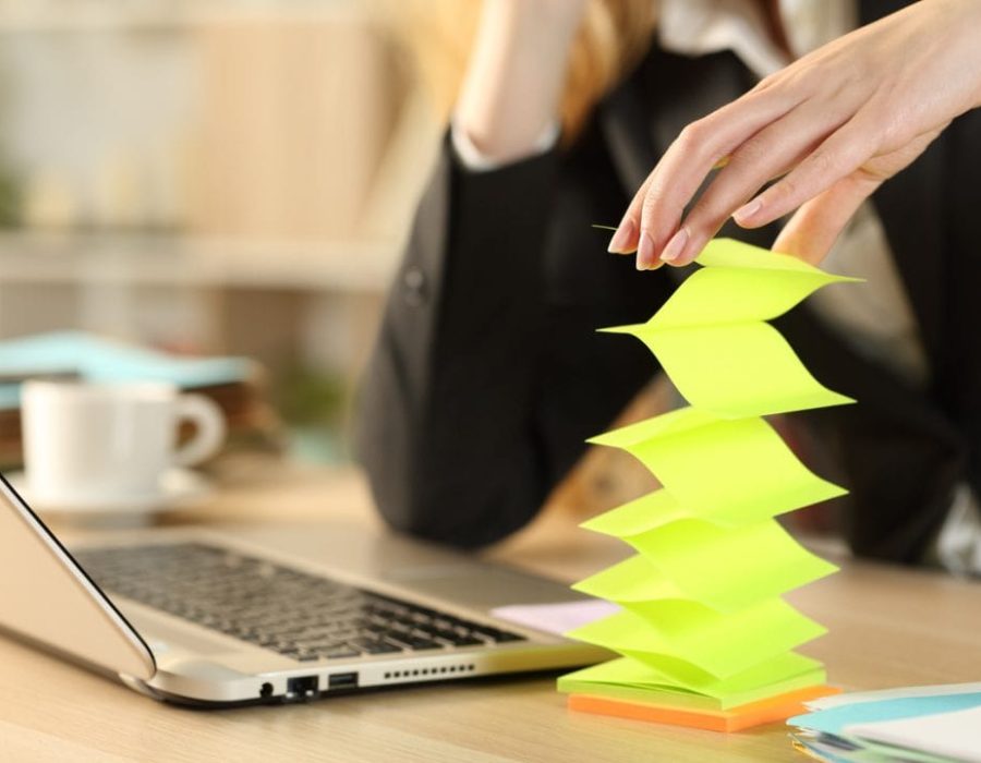 Bored lazy entrepreneur woman hands wasting time with post notes sitting on a desk